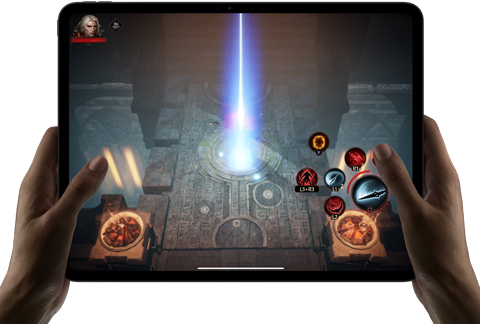 Two hands holding iPad Pro, displaying game with on screen touch controls and advanced graphics